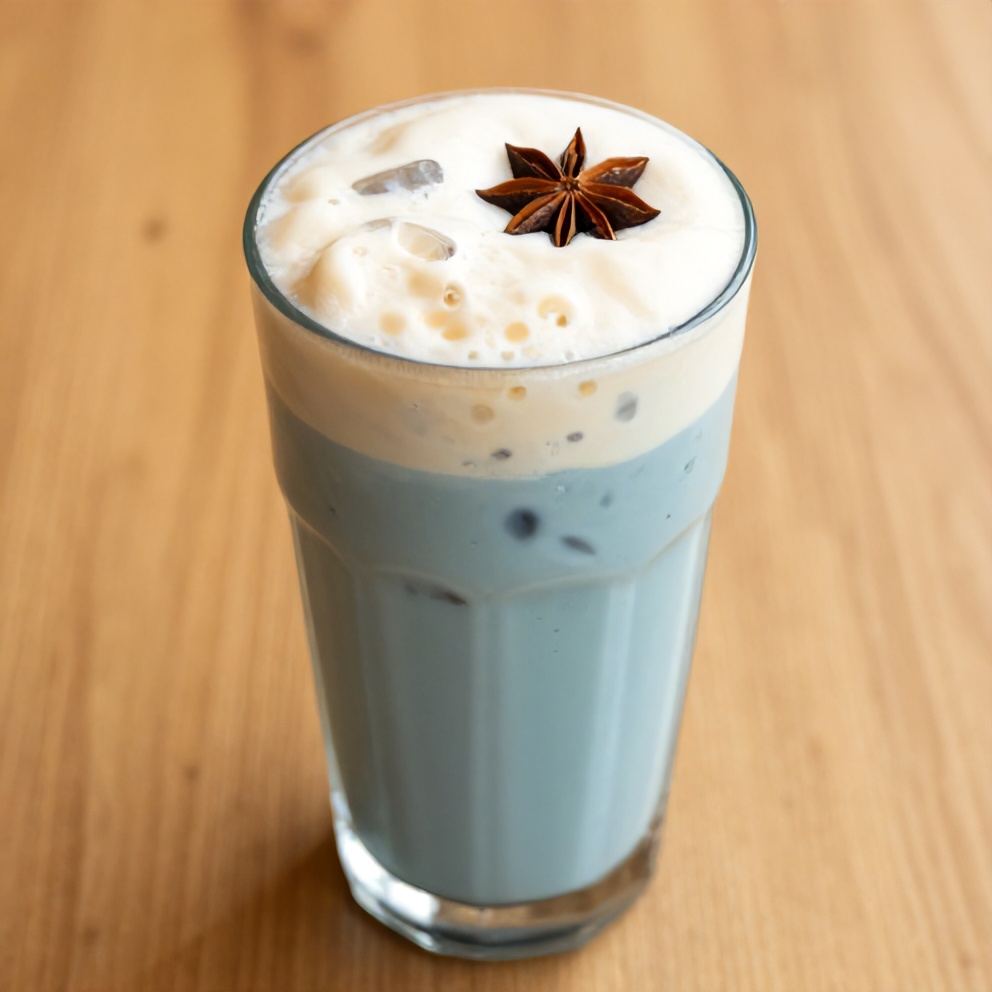 Iced blue tea latte with vanilla cold foam garnished with a straw and served in a glass