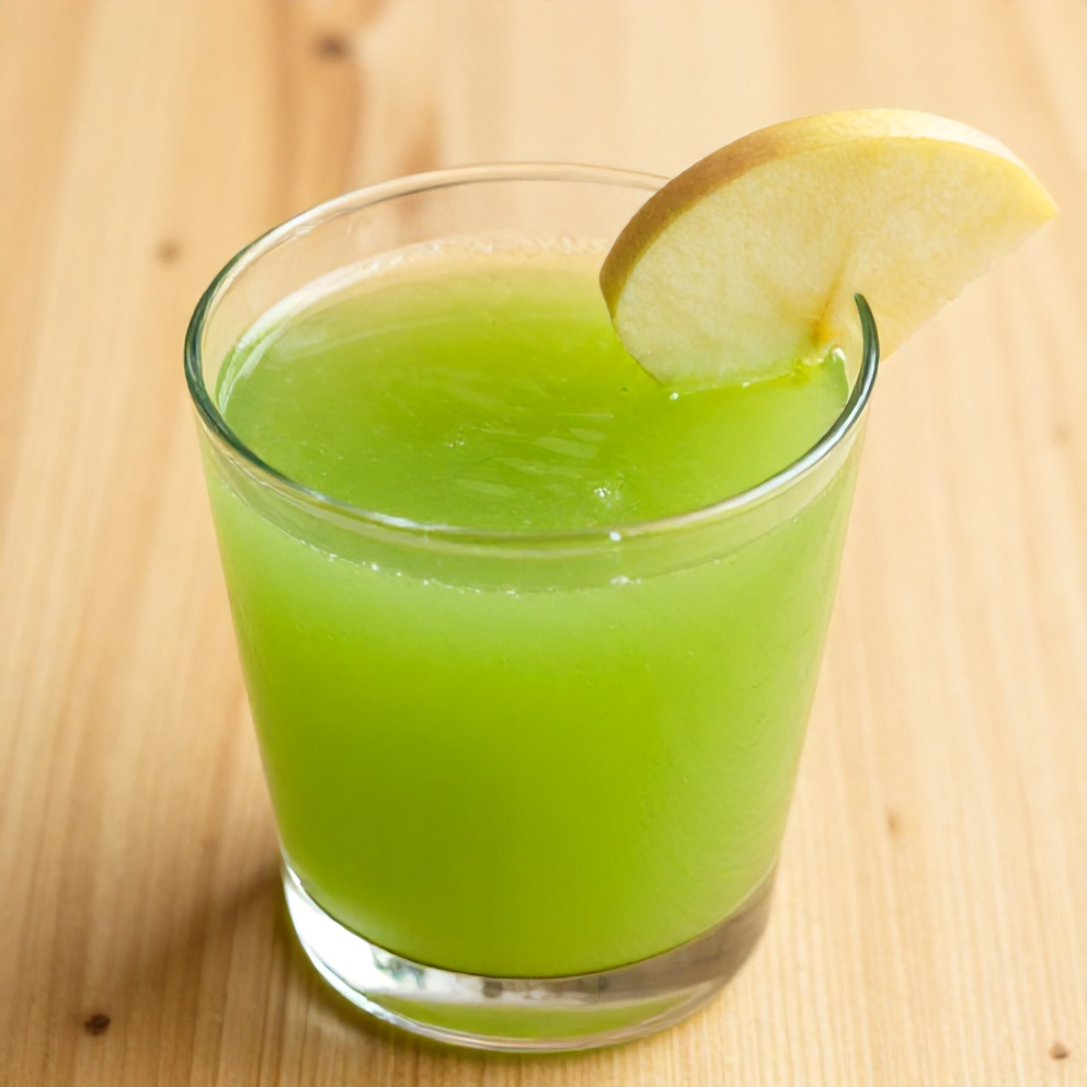 Glass of celery apple juice with a slice of apple on the rim